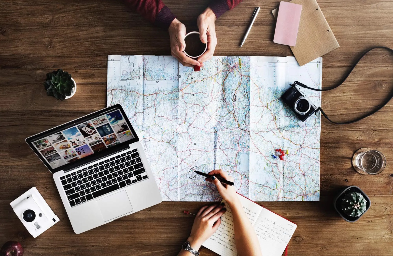 Travellers planning a journey together over a map with a camera and laptop