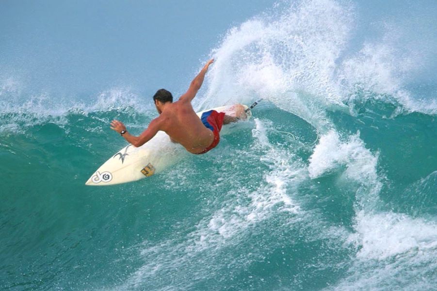 A surfer carving across a turquoise wave